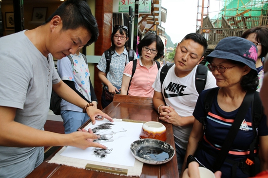 指画艺人李利峰（左）为游客展示手指作画。 .jpg