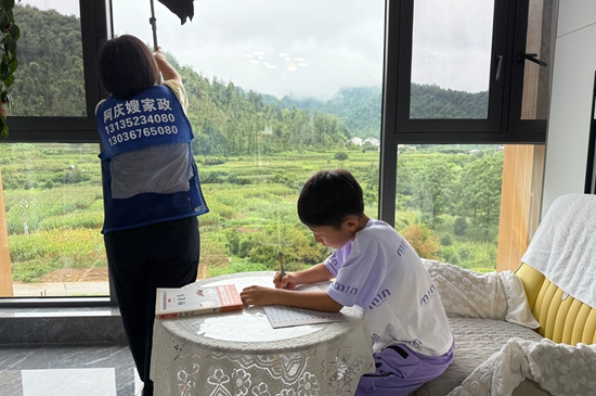 周绪萍在客户家打扫，儿子在一旁安静写作业。.jpg