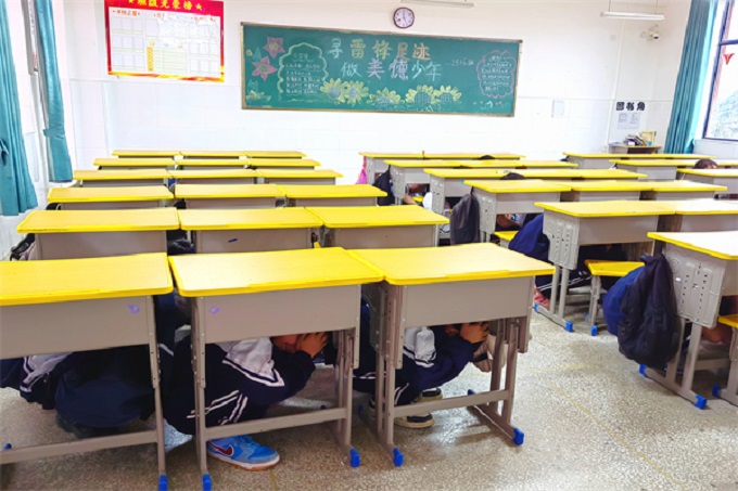 “地震”来临，学生们迅速蜷曲身体躲进桌子底下。.jpg