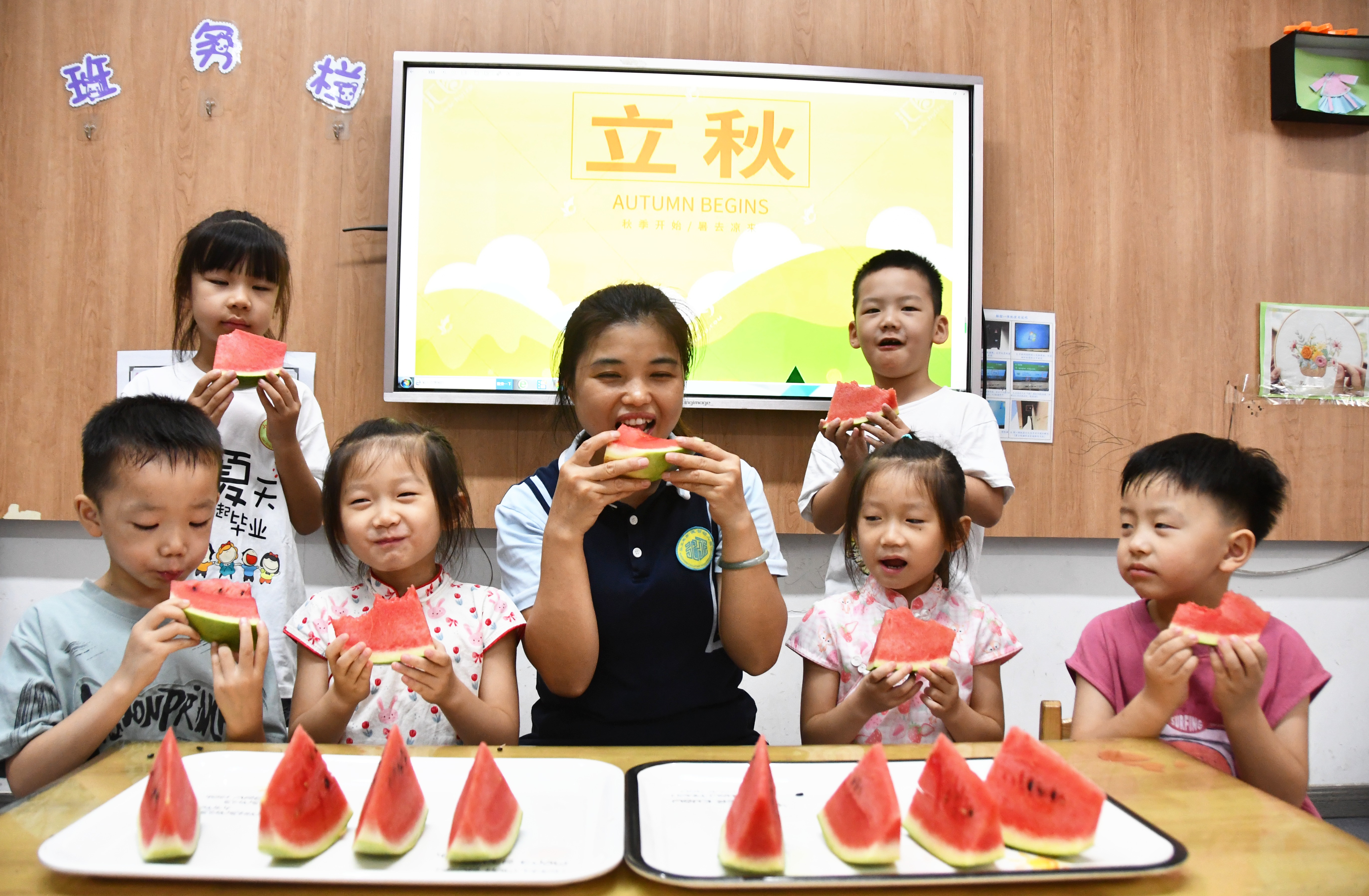 8月6日，湖南省永州市江永县潇浦镇德智幼儿园暑托班，老师和小朋友在吃西瓜“啃秋”。田如瑞摄.JPG