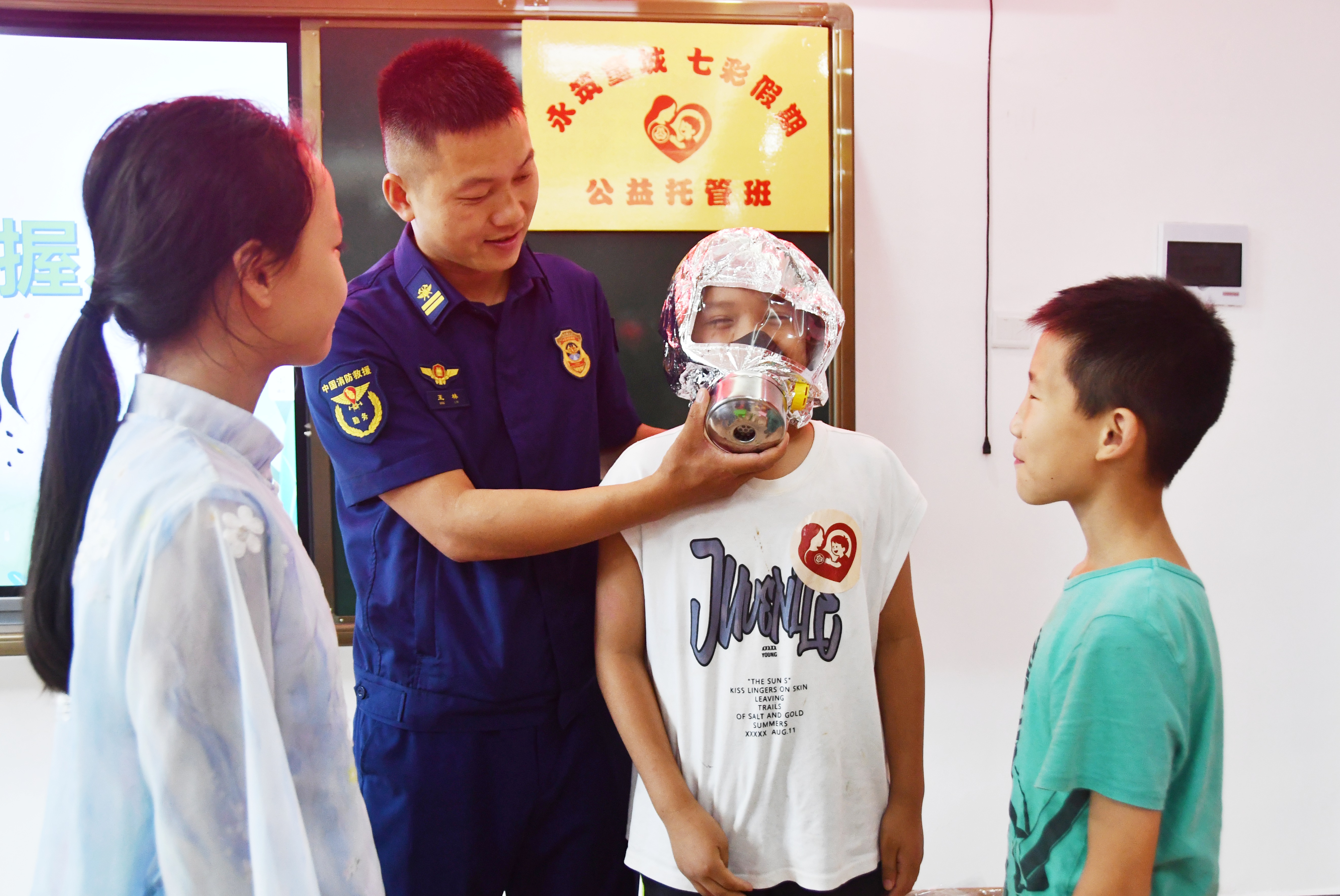 7月14日，湖南省永州市江永县潇浦镇永新社区爱心暑托班，消防救援队员向学生讲解防毒面具的佩戴方法。田如瑞摄4.JPG