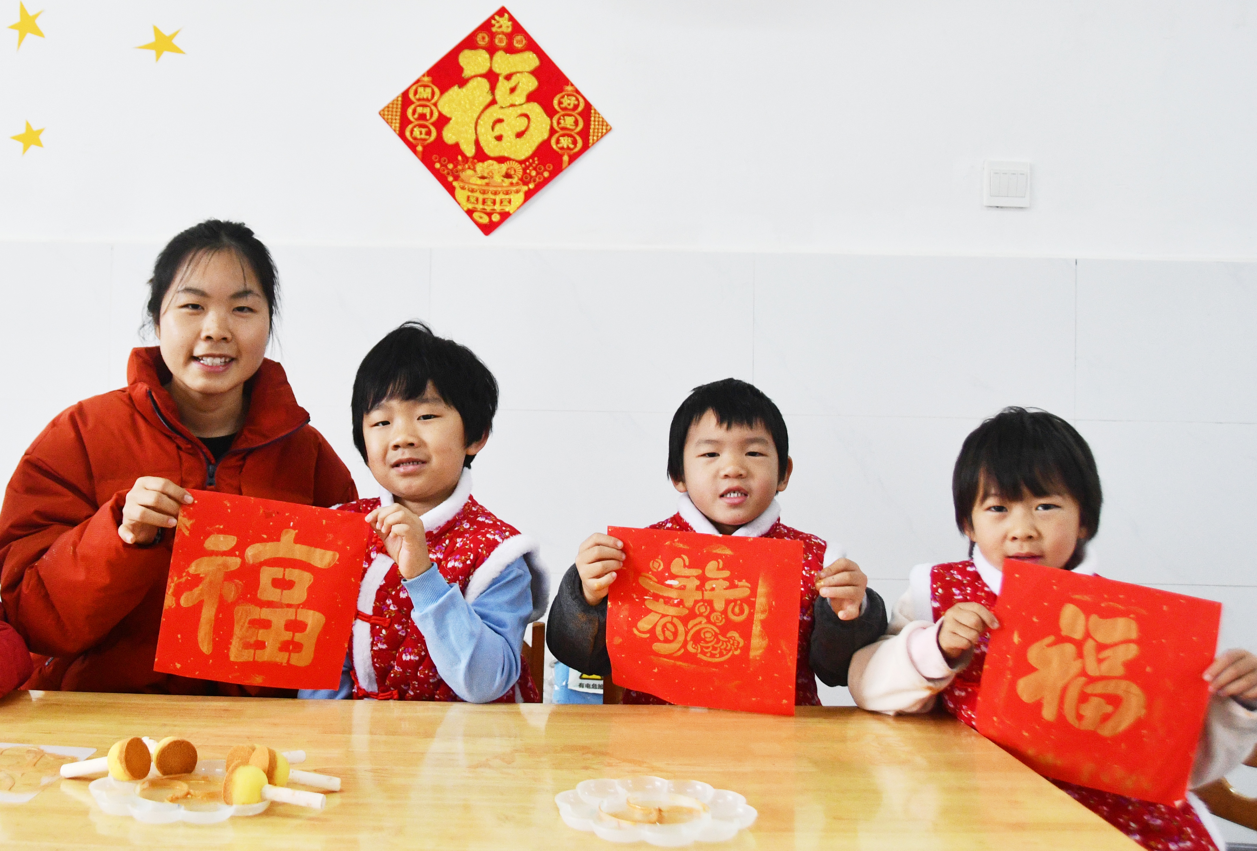 1月26日，在湖南省永州市江永县工业集中区幼儿园举办的腊八节活动上，老师指导小朋友拓印福字。田如瑞摄 (3).JPG