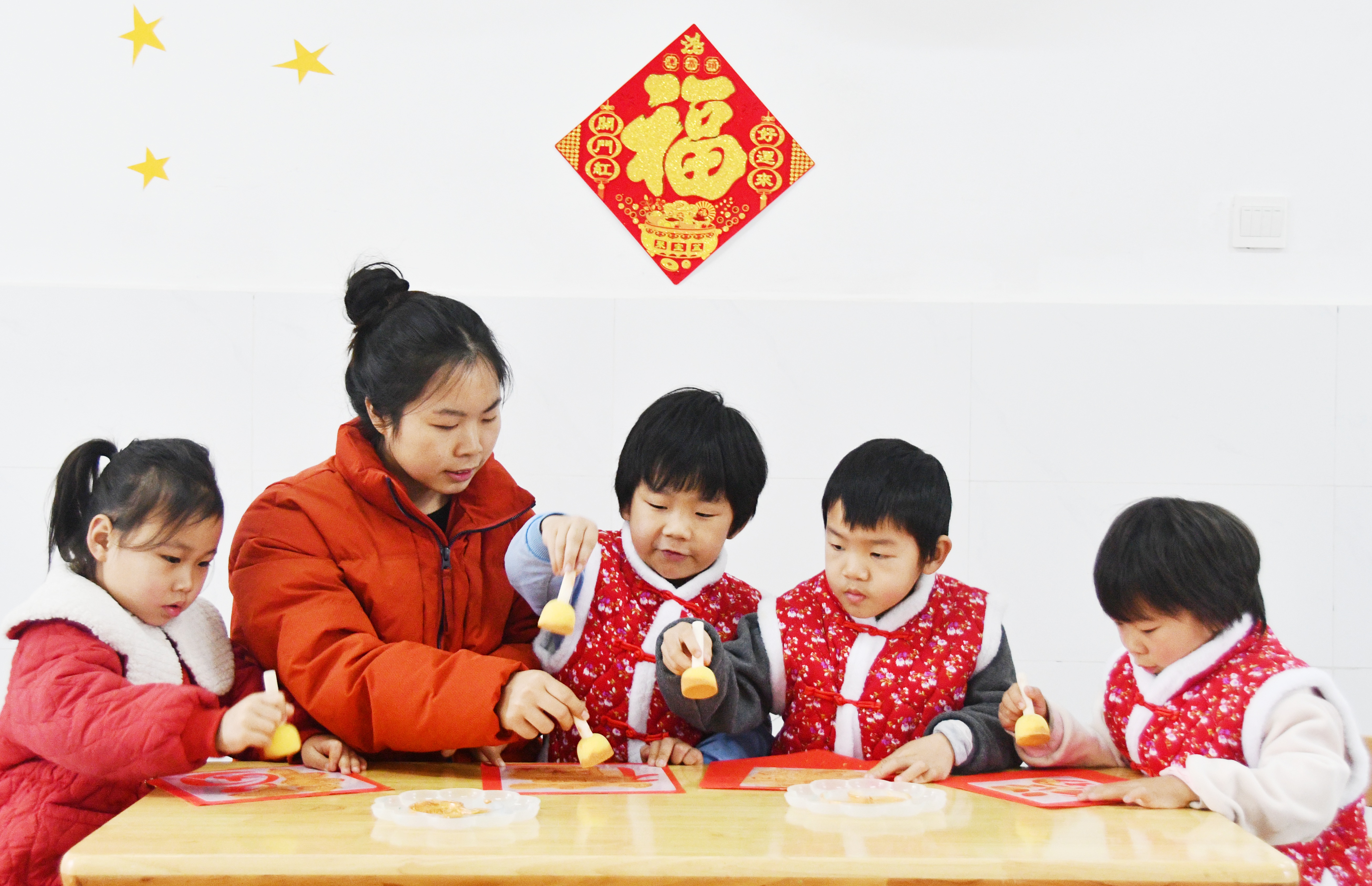 1月26日，在湖南省永州市江永县工业集中区幼儿园举办的腊八节活动上，老师指导小朋友拓印福字。田如瑞摄 (1).JPG