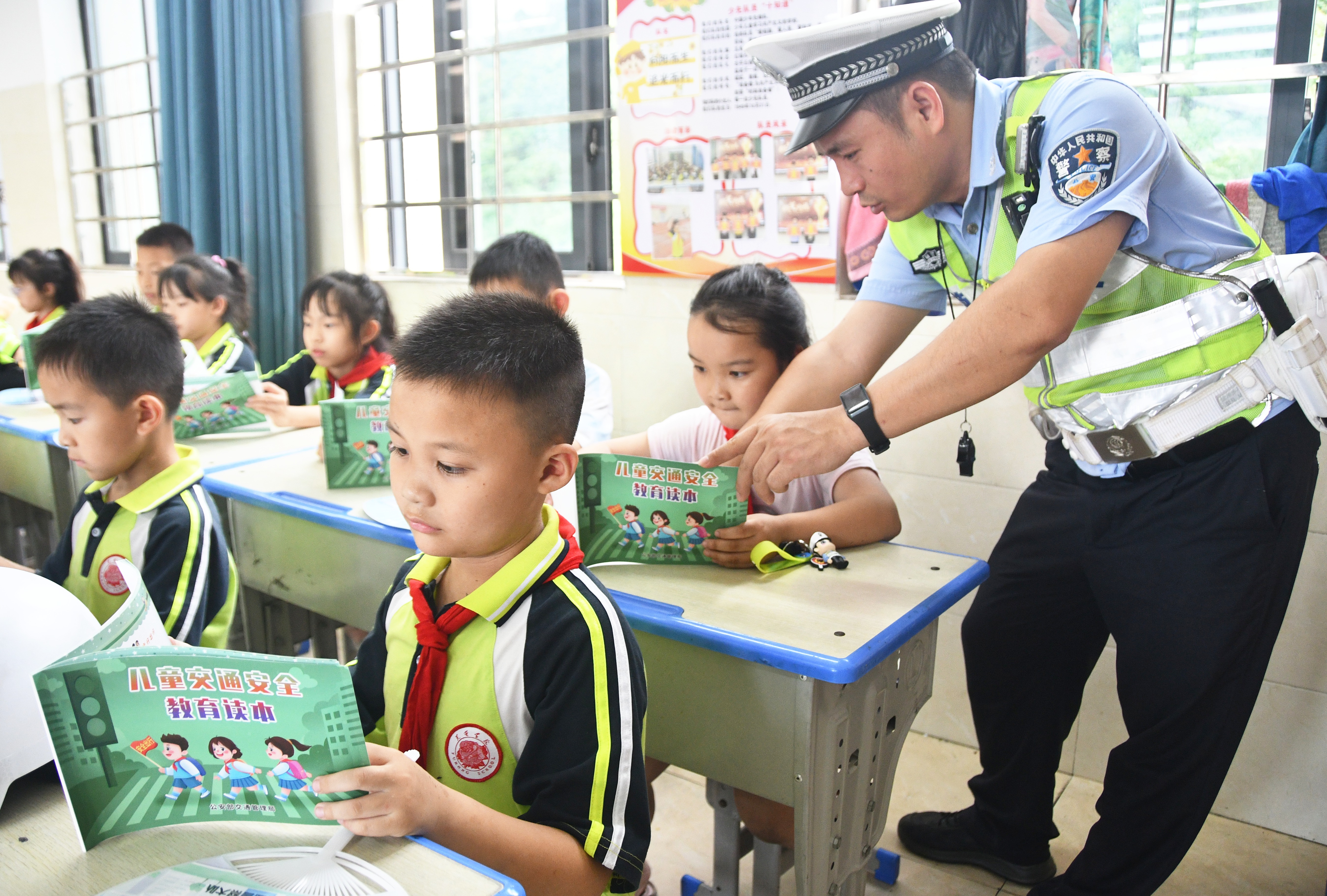 5月29日，在湖南省永州市江永县潇浦镇芙蓉学校，交警在指导小学生阅读儿童交通安全读本。田如瑞摄.JPG