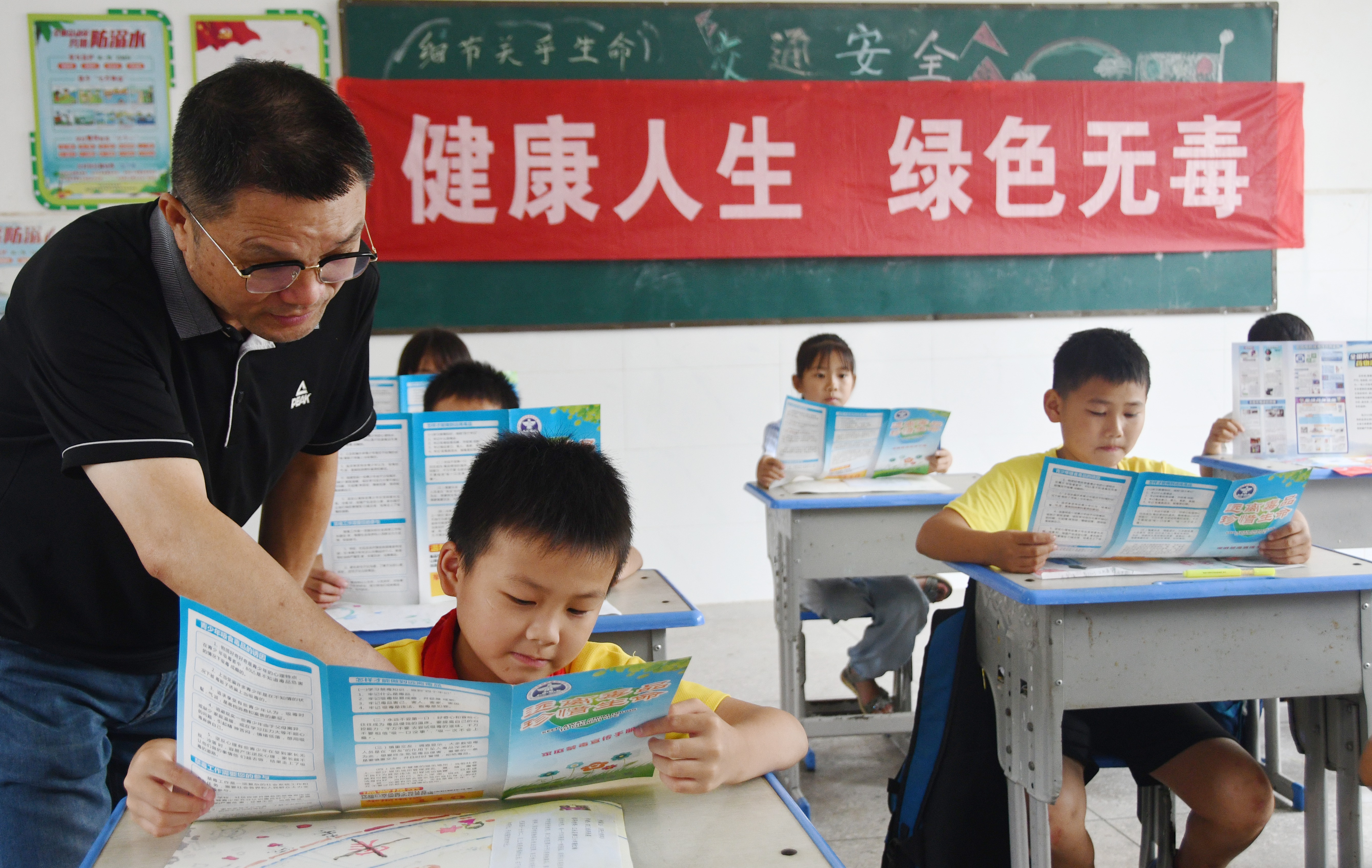 6月26日，湖南省永州市江永县海相希望小学，老师指导学生在阅读禁毒宣传资料。田如瑞摄 (1).JPG