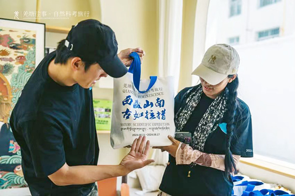 图为王子豪正在介绍印有科考之旅相关内容的挎包.jpg