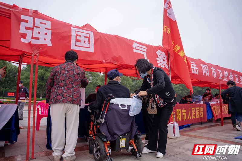 气象协会秘书长把科普宣传手册交给行动不方便群众。