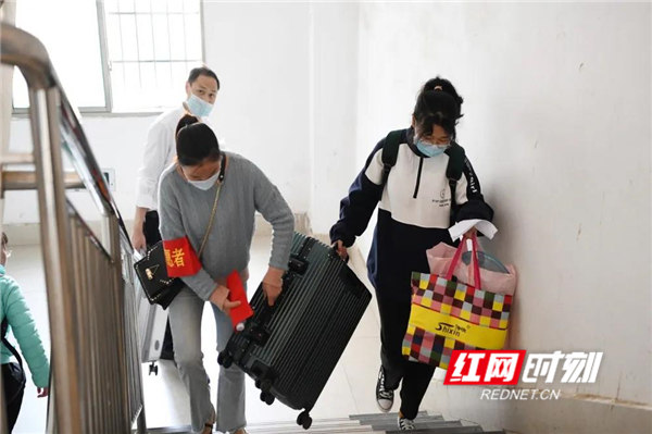 学生在志愿者的帮助下，携带行李进入到宿舍。