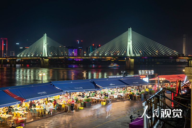 2020年5月31日，长沙，露天餐桌有序摆放在湘江渔人码头美食街上，食客一边品老长沙美食一边欣赏湘江夜景，人间烟火与城市繁华交织成了一道美丽的风景。