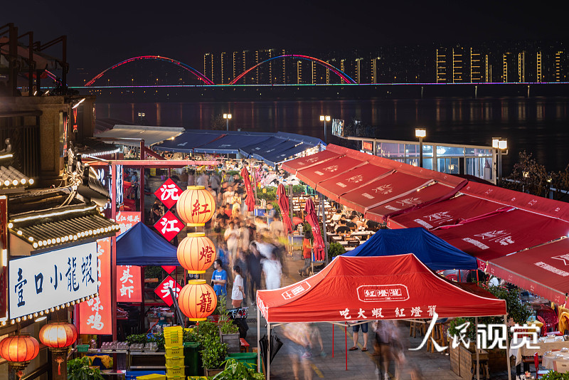 长沙,露天餐桌有序摆放在湘江渔人码头美食街上,食客一边品老长沙美食