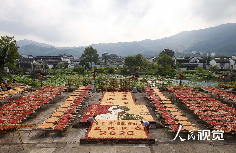 2020年8月27日，安徽省黄山市，呈坎古村村民在晒场上晾晒农作物。
近日，安徽省黄山市呈坎古村村民利用晴好天气，将收获归仓的玉米、黄豆、南瓜和红辣椒等五彩缤纷的果实，因地制宜晾晒在村中晒场，创意地拼出“国泰民安、风调雨顺”字样及战士、医护卡通形象，以农家特有的方式向祖国表达美好祝愿，向“最美逆行者”致敬。