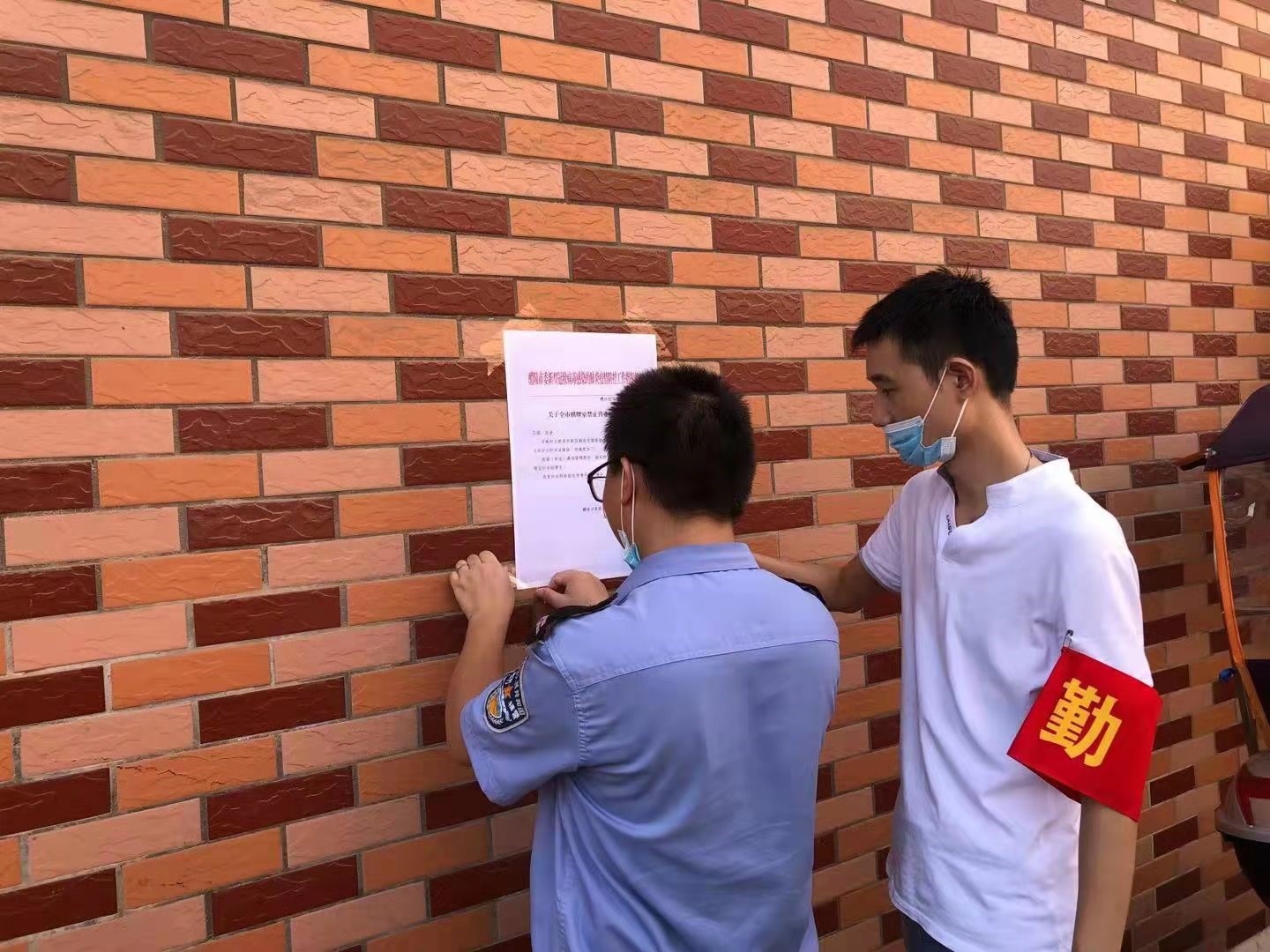 网格员与网格志愿者在格内粘贴防疫宣传标语.jpg
