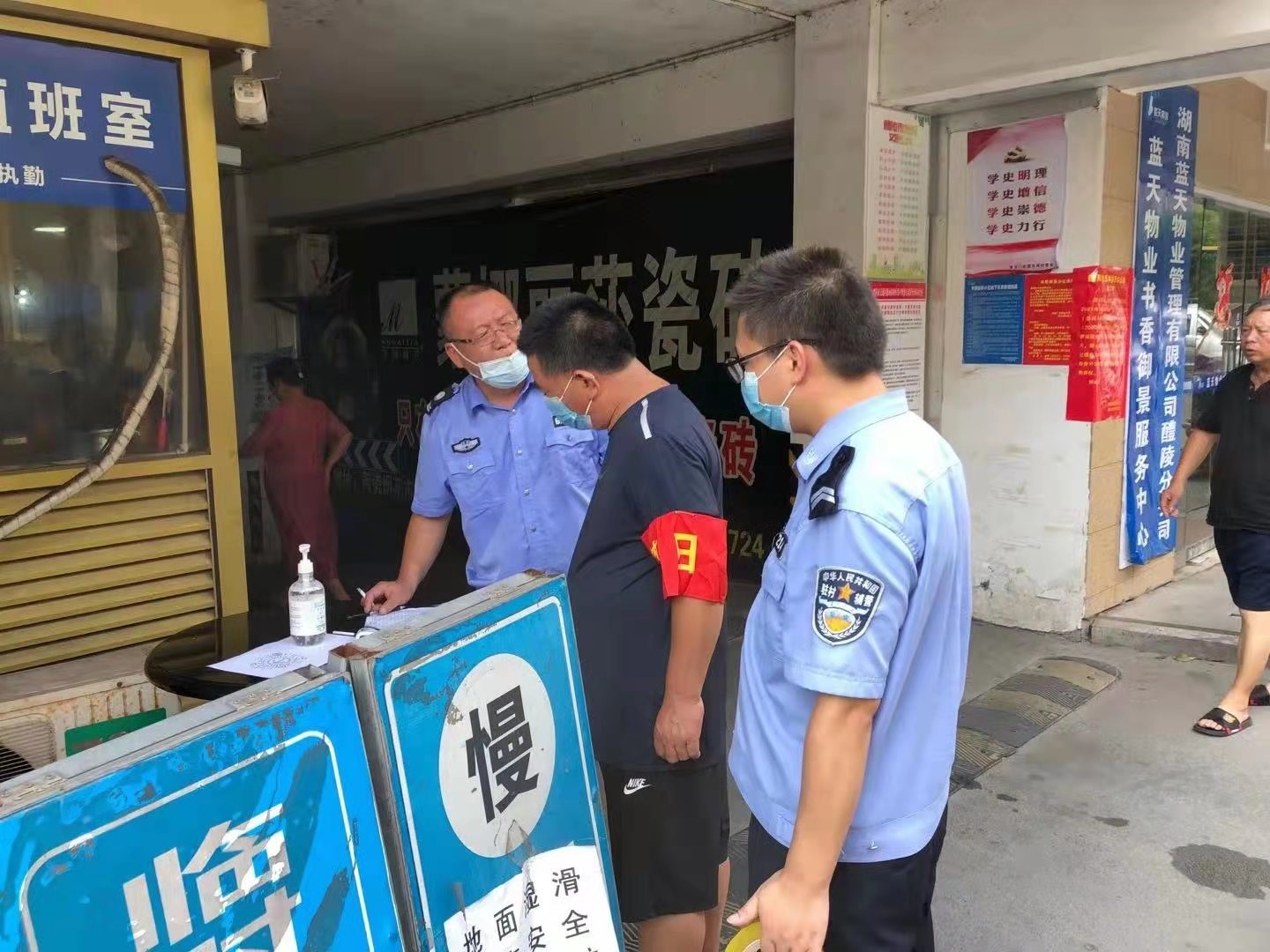 网格辅警与网格志愿者在小区门口查看防疫检测点.jpg