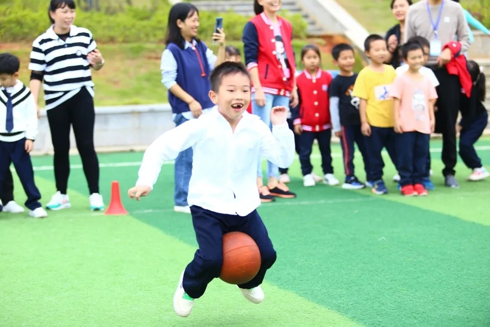 株洲天元小学，一名小运动员正双腿夹着球“带球跑”。