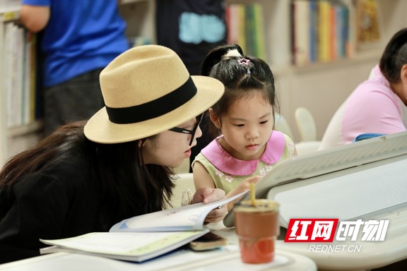 书城阅读区，母女俩头挨头，共赏绘本，温馨共读里满是夏日清凉与亲子情 。.marked.jpg