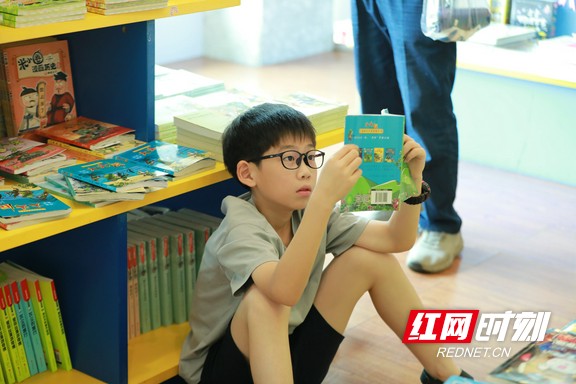 小男孩在书架旁席地而坐，捧着书仔细端详，在字里行间探寻乐趣 。.marked.jpg