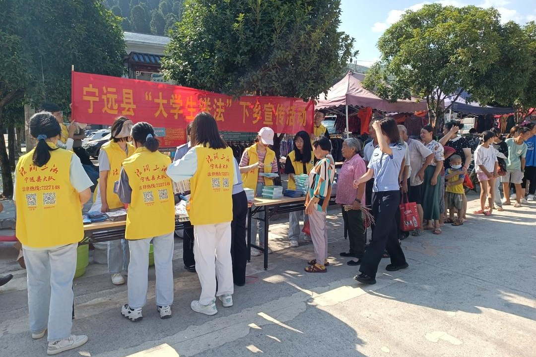 7月13日，永州宁远县司法局组织大学生普法志愿者在九疑山瑶族乡开展“送法下乡”活动。他们将法律服务热线及平台二维码印在志愿者背心上，颜色亮丽引人注目，群众纷纷扫码保存。