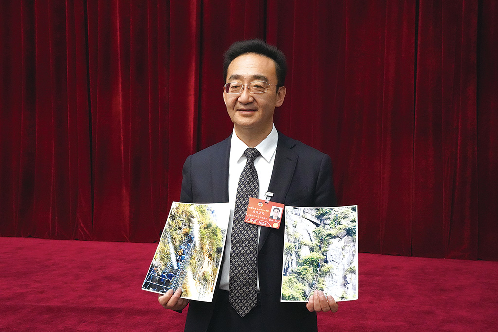 益西达瓦在联组会后展示“悬崖村”照片。李晗雪 摄.jpg