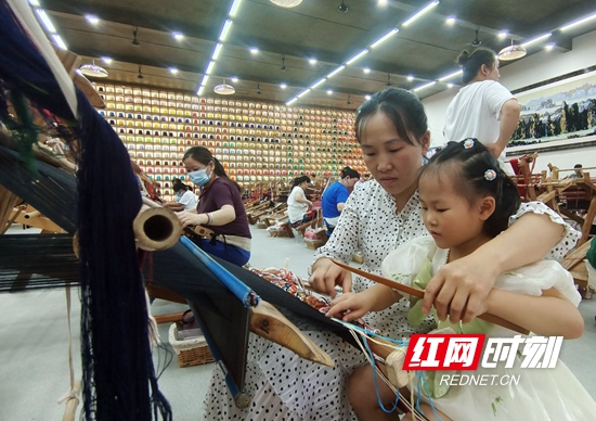 在“妈妈工坊”,从事织锦8年多的杨水莲在工余时间教5岁的女儿学习织锦。吴勇兵摄.jpg 在“妈妈工坊”,从事织锦8年多的杨水莲在工余时间教5岁的女儿学习织锦。吴勇兵摄.jpg
