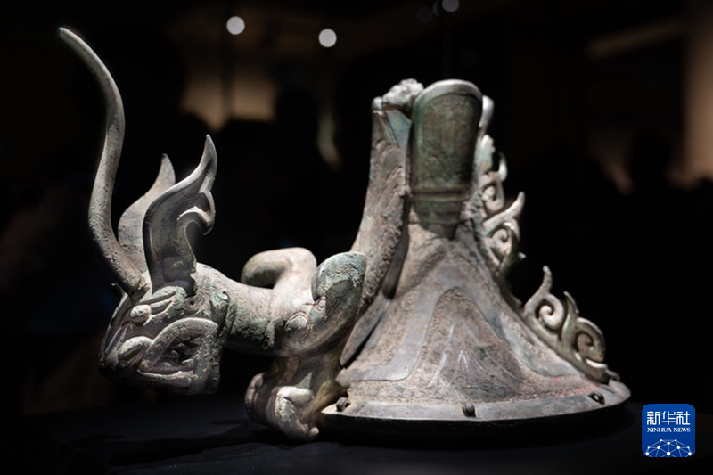 三星堆青铜鸟足神像的朱砂彩绘觚形尊上有一爬龙器盖，龙俯身在青铜立人脚下。.jpg