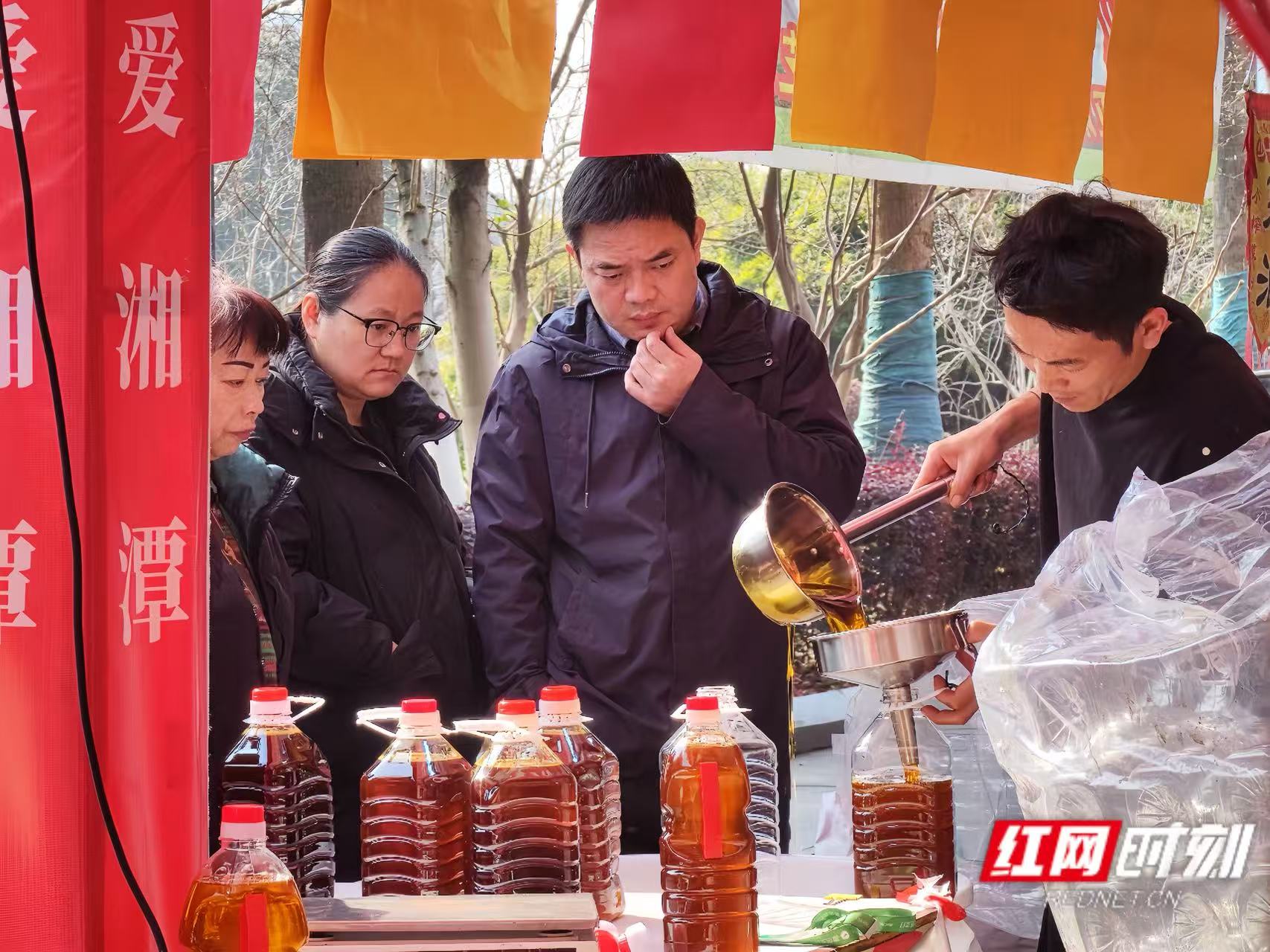现榨油坊的摊位前，市民们正在等待购买的油装瓶。.jpg