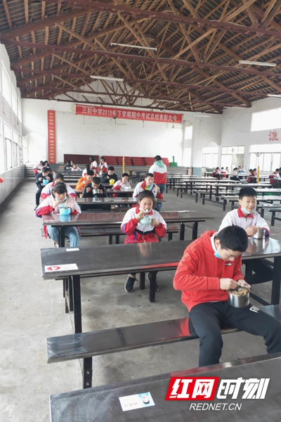 华容县三封寺镇三封中学，学生中午在食堂门口分班错时就餐，间隔1米排成三队，再次体温检测、登记，按“品”字型落座，相互错开，确保师生安全。