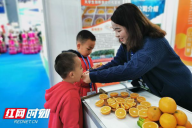 芷江橙家班桔业展位前，小朋友们现场尝试刚采摘下来的冰糖橙，大呼“好吃”！