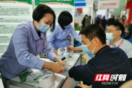 在怀化市第一人民医院展位前，工作人员为前来参观的嘉宾测量血压。