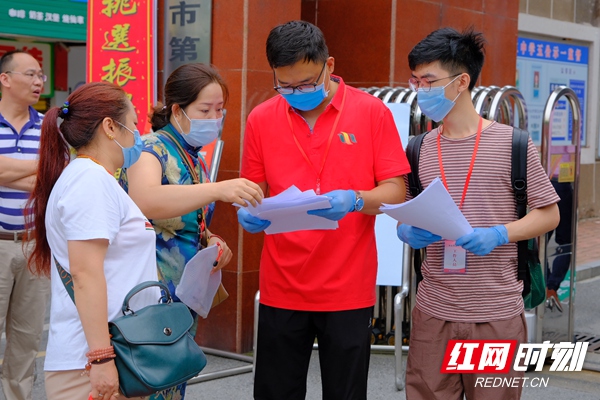 考场工作人员与带队前来考试的老师仔细核对考生信息及体温测量情况。刘小林 摄
