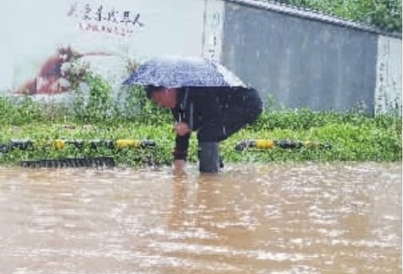 暴雨赶上早高峰 热心人撑伞守井盖