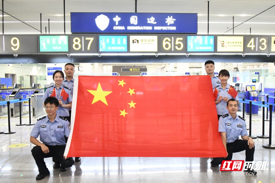 在勤务间隙，执勤三队民警与国旗合影，展现新时代移民管理警察队伍风采和良好形象，抒发对祖国的热爱，为祖国献上最诚挚的祝福。 (2).JPG