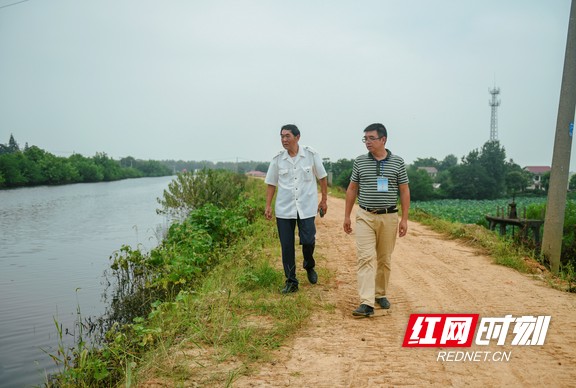 上阵父子兵，区防汛技术人员谢海涛父子正在沿堤巡查