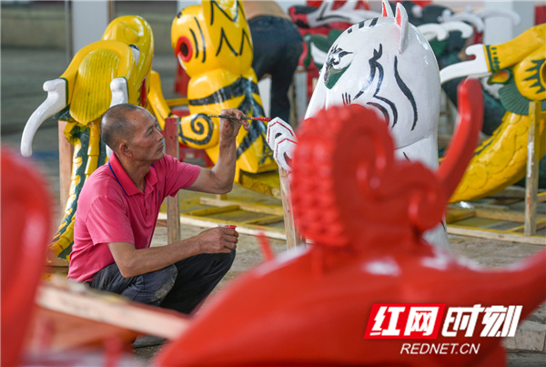 龙船头雕刻手艺人陈兵寿在给龙船的旧“龙头”裱漆。