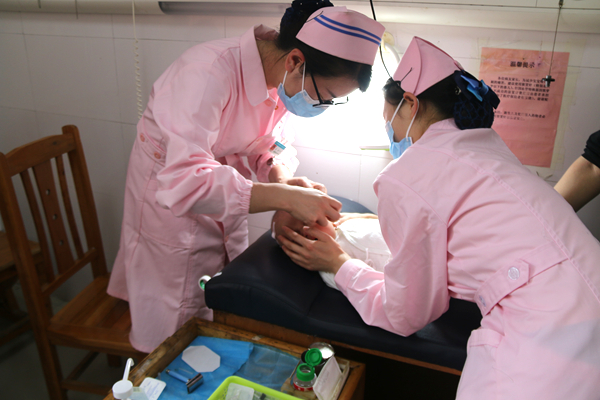 5月9日，新田县人民医院新生儿科护士王云（左）与同事，一起为婴儿进行头皮静脉穿刺。 郑有为摄.JPG