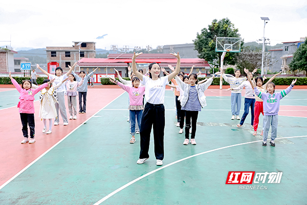 平安人寿湖南分公司支教志愿者强小娟在操场开设小课堂，教孩子们跳舞。