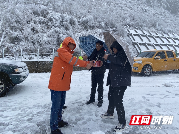 因强降雪导致该处长下坡路段积雪，车辆出现滞留，养护人员为滞留司乘赠送饮用水和方便面。