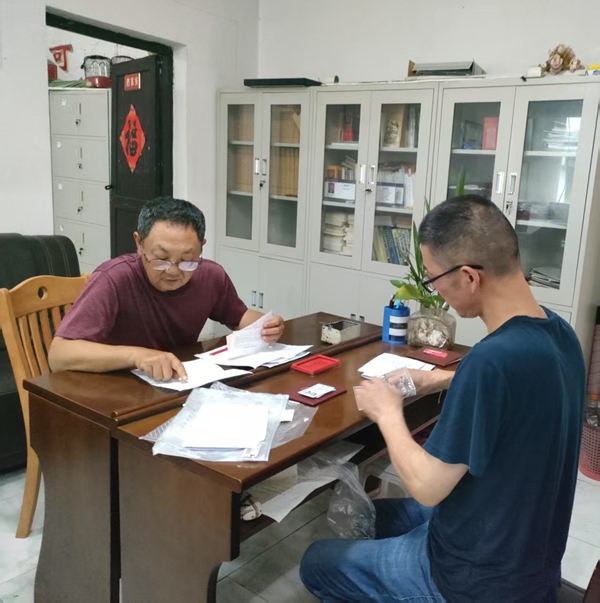 糜红武（左）在仔细审核当事人办证的证明材料。.jpg