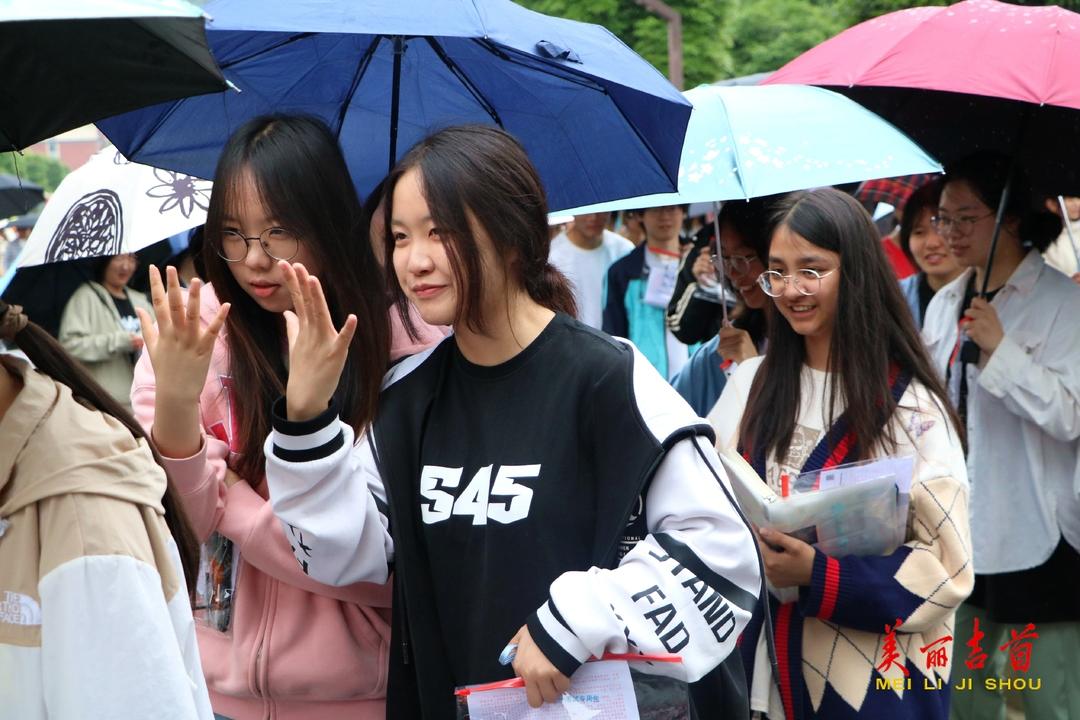 6月8日上午，雨伞下，两名女生亮出手掌，凝视前方，相互鼓劲要手到擒来。