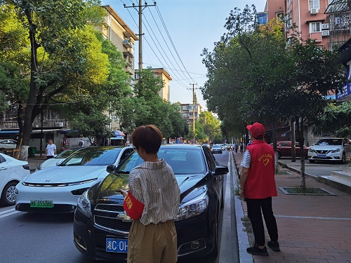 志愿者在月桂街劝离违规停放的送学车辆.jpg