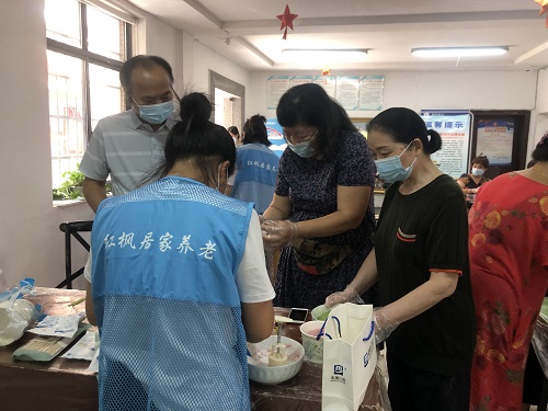 第一次做月饼的阿姨们围在志愿者身前，认真的听着制作步骤.jpg