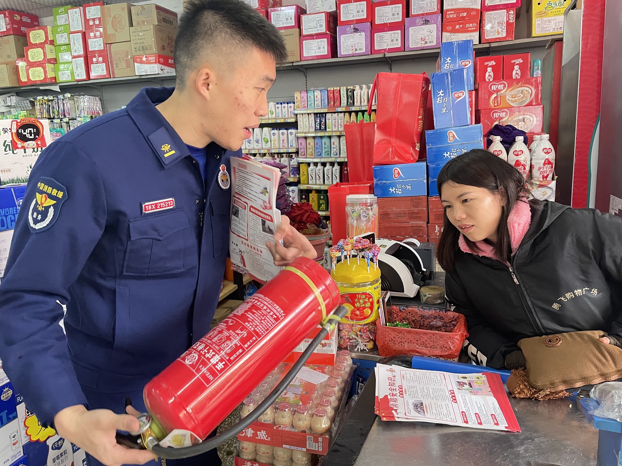 零陵区消防救援大队组织宣传服务队员为商铺店主讲解灭火器的使用方法和注意事项。