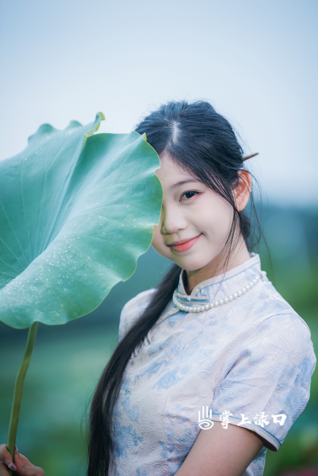 【图：文禹  文：刘慧】
立于荷塘之畔，轻执一片硕大荷叶，碧叶衬得眉眼恬淡，笑意温柔，与一池荷韵相映，揉碎了夏日的温柔与烂漫。
