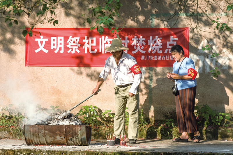淮川街道城西社区文明祭祀临时焚烧点，志愿者正在整理焚烧残余。贺再亮摄