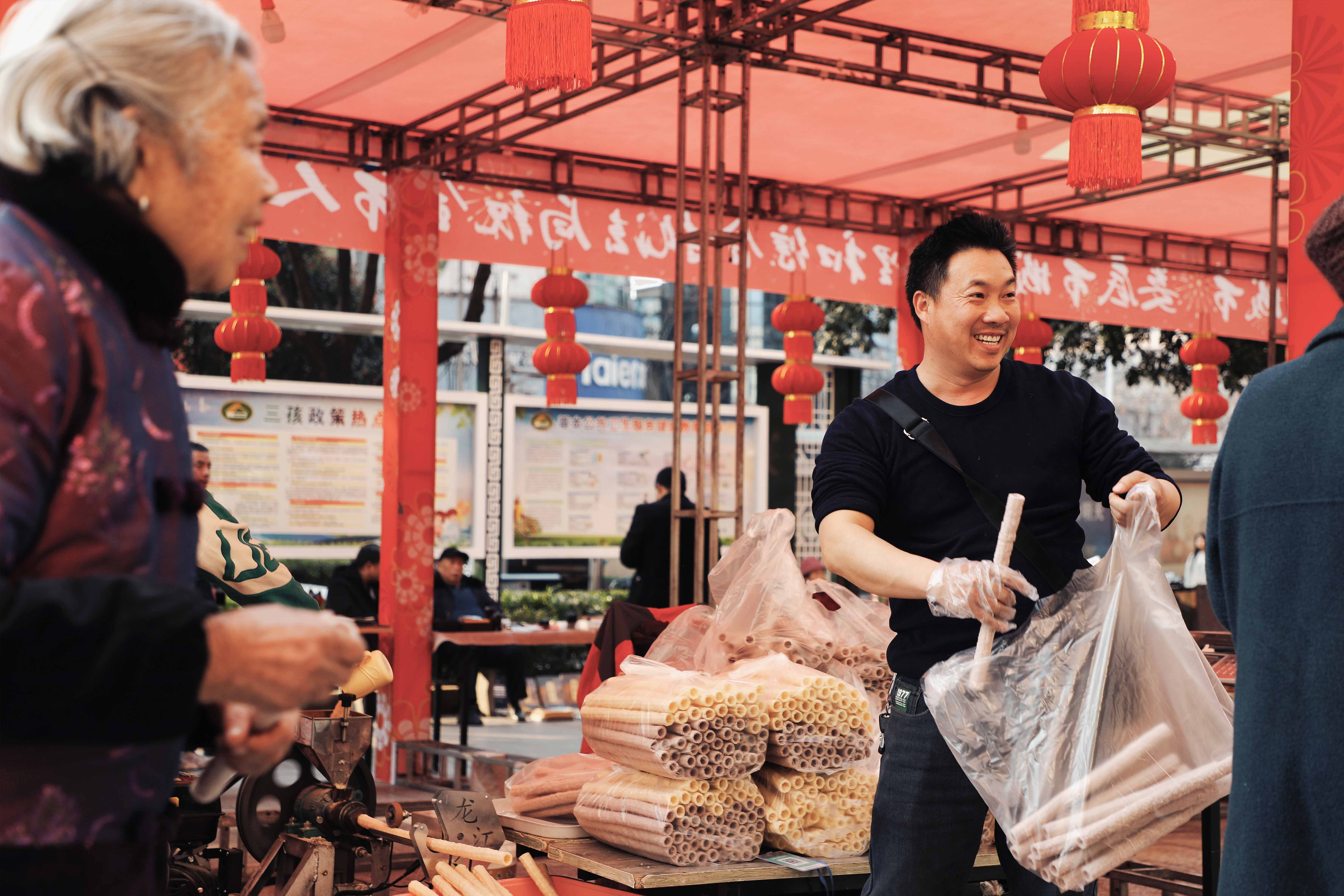 “便民迎新春”年味集市上，“童年回忆”米花筒，让老人小孩驻足品尝。你小时候吃过吗？